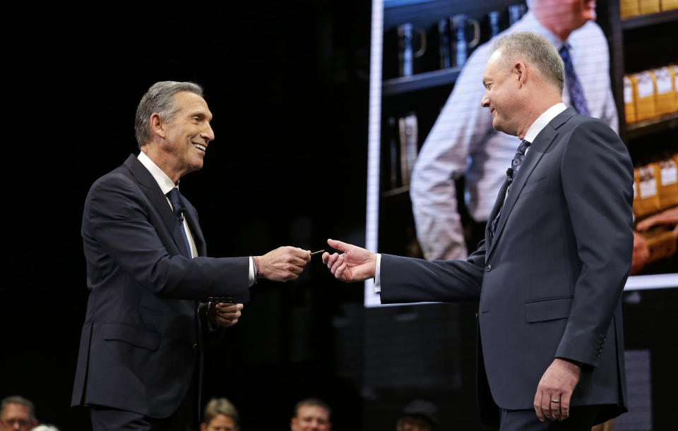 Howard Schultz, left, hands over the door key of the Pike Place Market Starbucks' store to Kevin Johnson at the company's annual shareholders meeting, Wednesday, March 22, 2017, in Seattle. (AP Photo/Elaine Thompson)