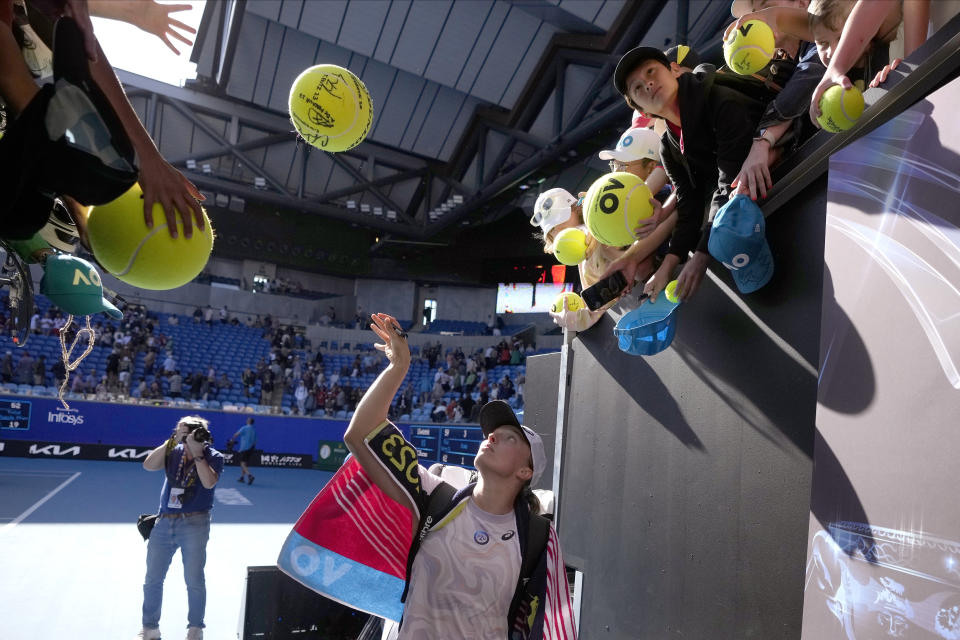 Iga Swiatek of Poland signs autographs after defeating Cristina Bucsa of Spain in their third round match at the Australian Open tennis championship in Melbourne, Australia, Friday, Jan. 20, 2023. (AP Photo/Dita Alangkara)