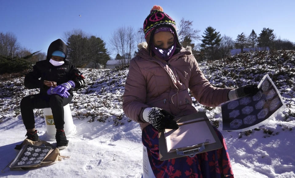 In this Monday, Dec. 8, 2020 photo, fourth grader Falis Asair, right, makes notes about snowflakes during an outdoor class at the Gerald Talbot School, in Portland, Maine. Across the country, schools scrambled to get students outdoors during the pandemic to keep them safe and stop the spread of COVID-19.(AP Photo/Robert F. Bukaty)