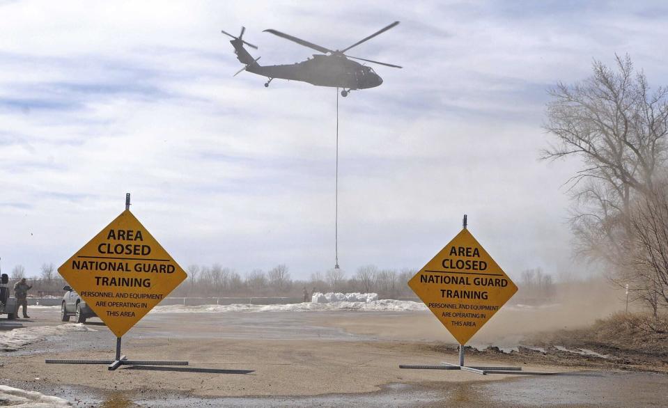 A Black Hawk helicopter with the North Dakota National Guard's Company C, 2nd Battalion, 285th Aviation Regiment prepares to lift a one-ton sandbag during training at Kimball Bottoms south of Bismarck, N.D., on Wednesday, April 12, 2023. Guard aviators use the large sandbags to block water and slow erosion during emergency flood response operations. The Guard on Wednesday also diverted a Black Hawk to help with local flooding mitigation in the White Earth area, east of Tioga in northwestern North Dakota. The helicopter dropped sandbags to plug a drainage culvert. (Tom Stromme/The Bismarck Tribune via AP)