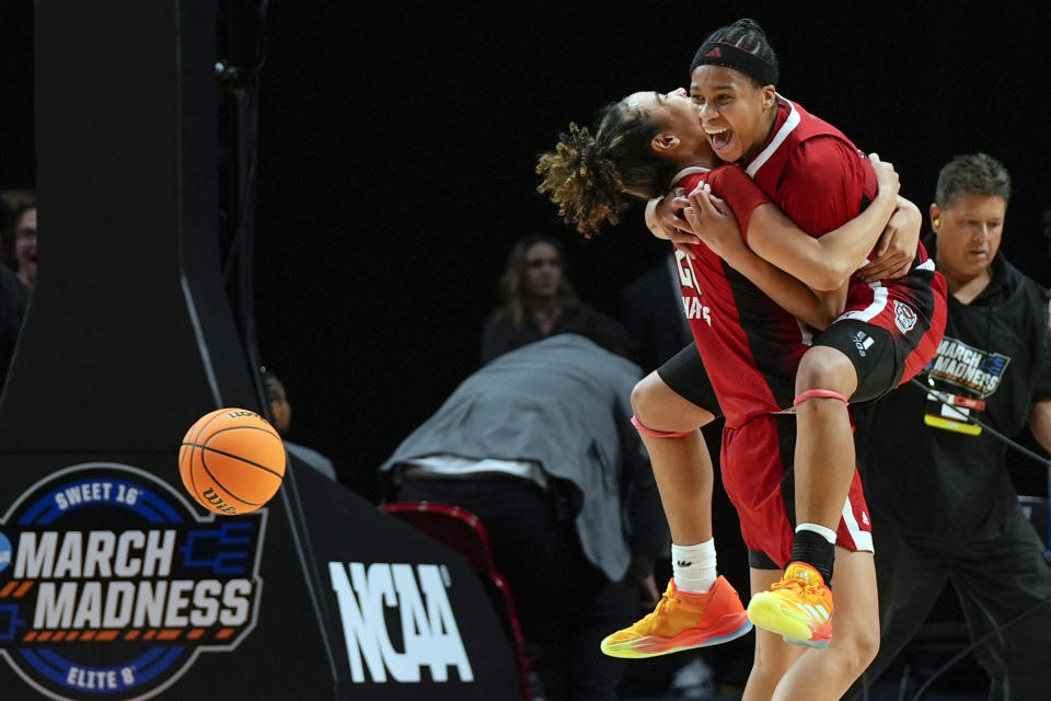 North Carolina State guard Madison Hayes, left, holds North Carolina State guard Zoe Brooks as they celebrate after a Sweet 16 college basketball game against Stanford in the women's NCAA Tournament, Friday, March 29, 2024, in Portland, Ore. North Carolina State won 77-67. (AP Photo/Jenny Kane)