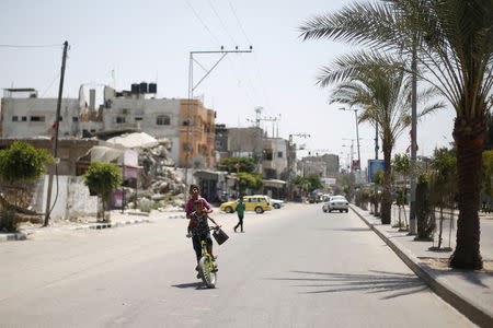 Palestinian boys ride a bicycle on a street in Beit Hanoun town, ahead of the first anniversary of the 50-day war, in the northern Gaza Strip July 6, 2015. REUTERS/Suhaib Salem