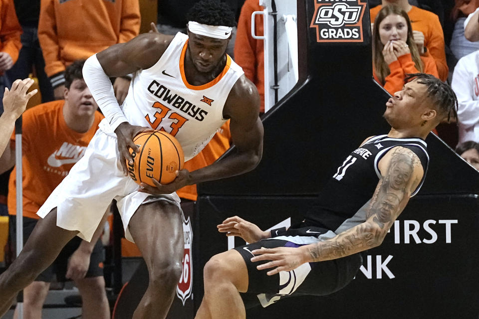 Oklahoma State forward Moussa Cisse (33) fouls Kansas State forward Keyontae Johnson, right, in the first half of an NCAA college basketball game, Saturday, Feb. 25, 2023, in Stillwater, Okla. (AP Photo/Sue Ogrocki)