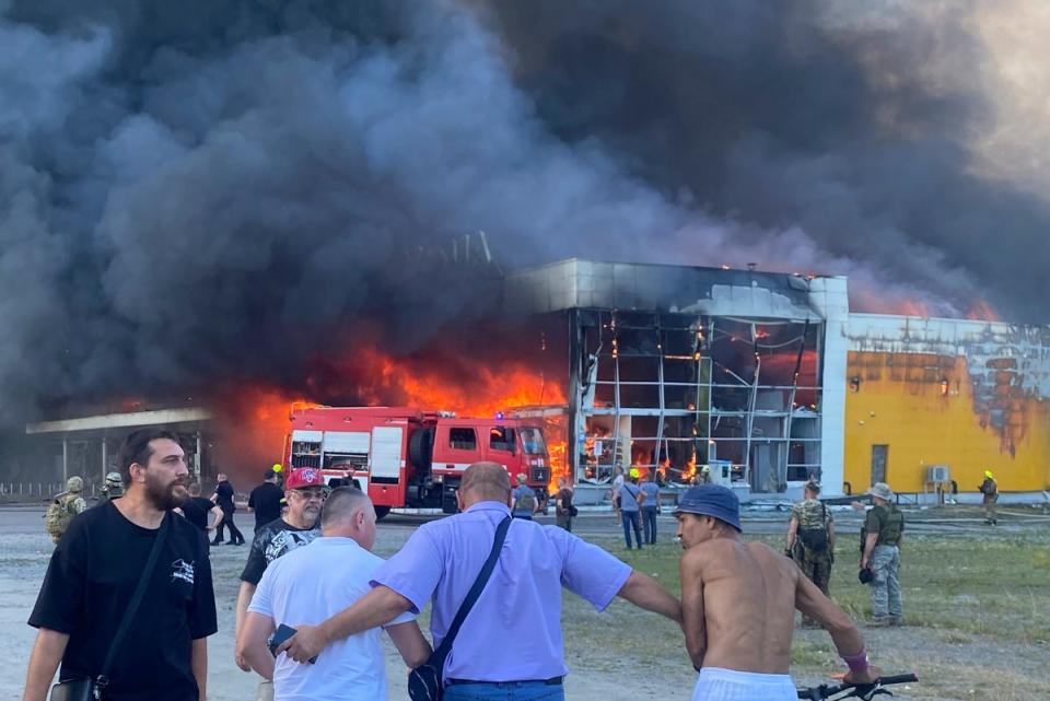 People watch as smoke bellows after a Russian missile strike hit a crowded shopping mall in Kremenchuk (Viacheslav Priadko/AP) (AP)