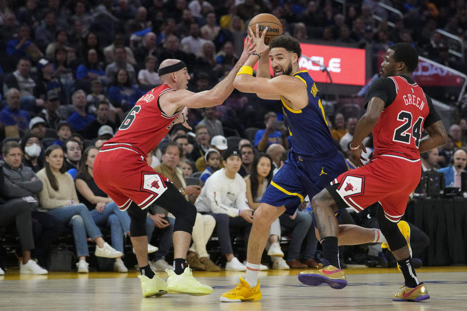 Golden State Warriors guard Klay Thompson, middle, moves past Chicago Bulls guard Alex Caruso (6) and forward Javonte Green (24) during the first half of an NBA basketball game in San Francisco, Friday, Dec. 2, 2022. (AP Photo/Godofredo A. Vásquez)