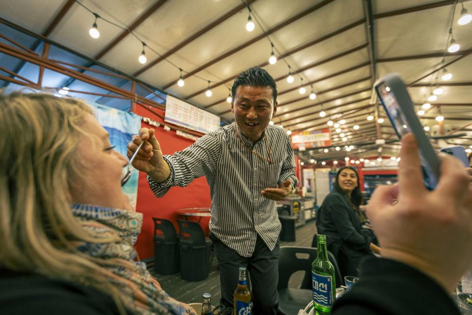 a man feeding a woman at a korean bbq restaurant in busan