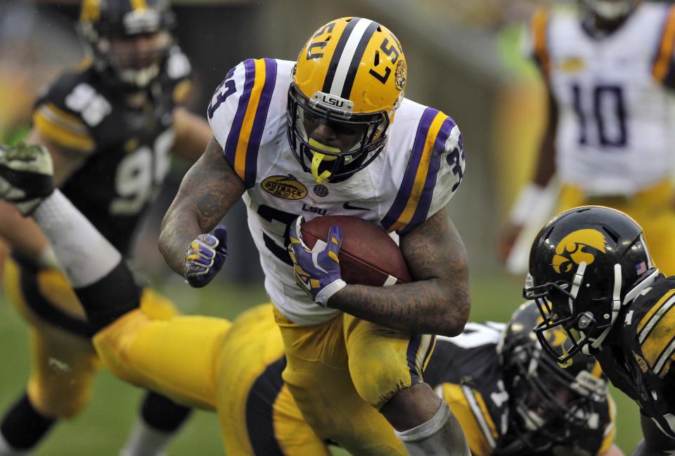 LSU running back Jeremy Hill (33) rushes through the Iowa defense, including defensive back Desmond King, right, to score on a 14-yard touchdown run during the second quarter of the Outback Bowl NCAA college football game Wednesday, Jan. 1, 2014, in Tampa, Fla. (AP Photo/Chris O'Meara)