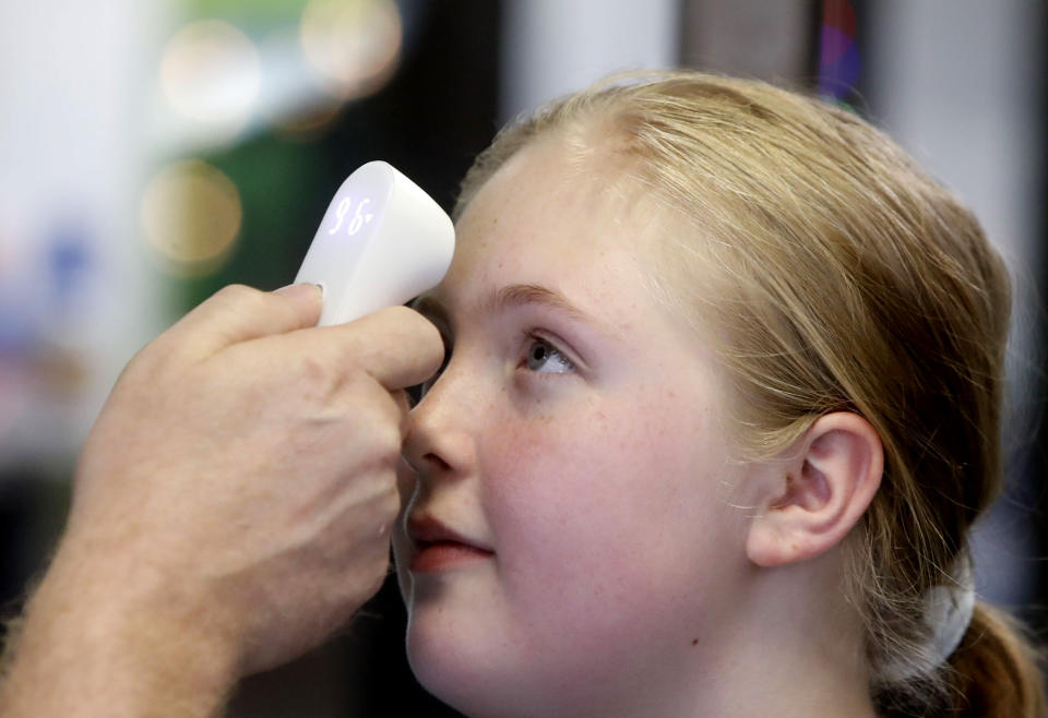 Kaiden Melton, 12, has her temperature taken during a daycare summer camp at Legendary Blackbelt Academy in Richardson, Texas, Tuesday, May 19, 2020. As daycares and youth camps re-open in Texas, operators are following appropriate safety measure to insure kids stay safe from COVID-19. (AP Photo/LM Otero)