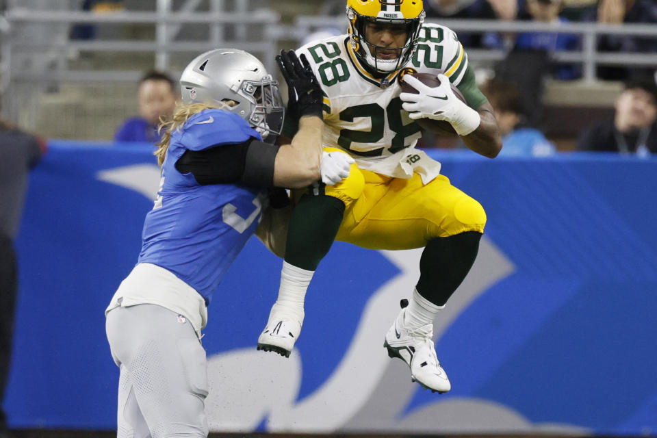 Green Bay Packers running back AJ Dillon (28) makes a reception as Detroit Lions linebacker Alex Anzalone defends during the first half of an NFL football game, Thursday, Nov. 23, 2023, in Detroit. (AP Photo/Duane Burleson)