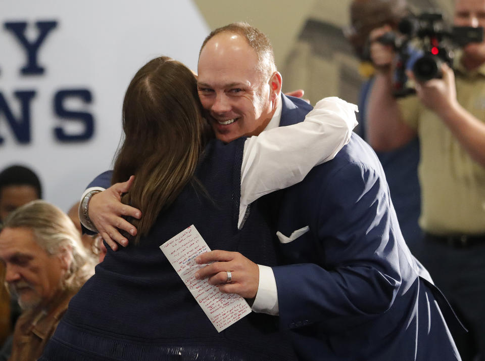 Newly hired Georgia Tech football coach Geoff Collins gets a hug from a family member before speaking at a news conference Friday, Dec. 7, 2018, in Atlanta. (AP Photo/John Bazemore)