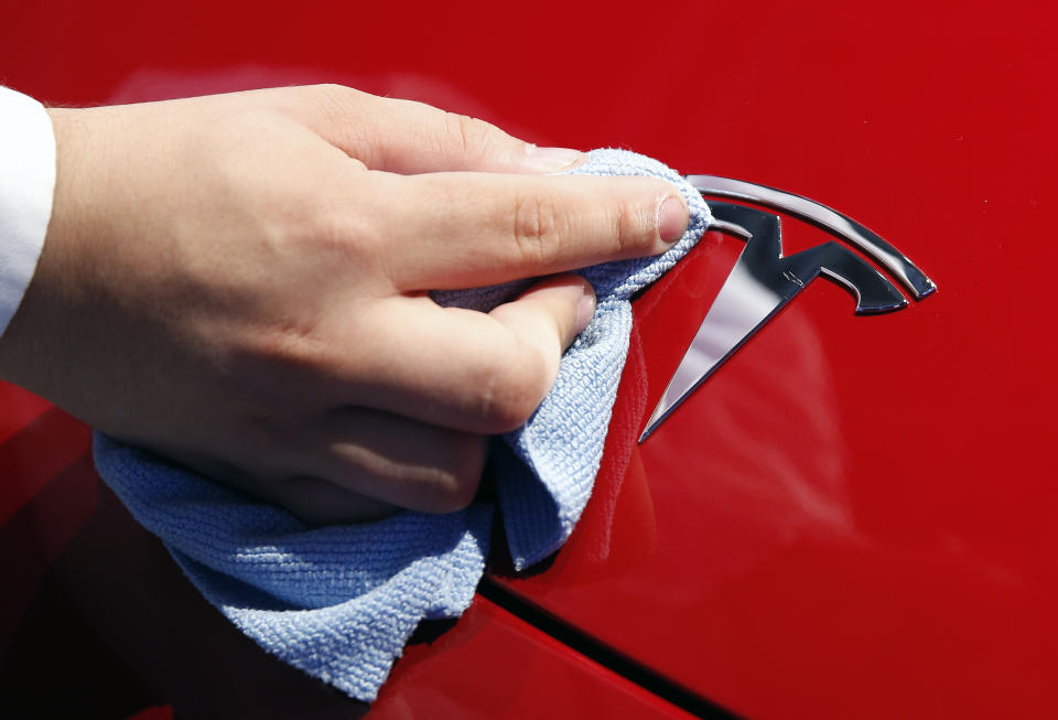 An employee cleans the logo of a Tesla Model 3 automobile during the first press day of the Paris Motor Show at the Parc des Expositions at the Porte de Versailles on October 2, 2018 in Paris. (Photo by Chesnot/Getty Images)