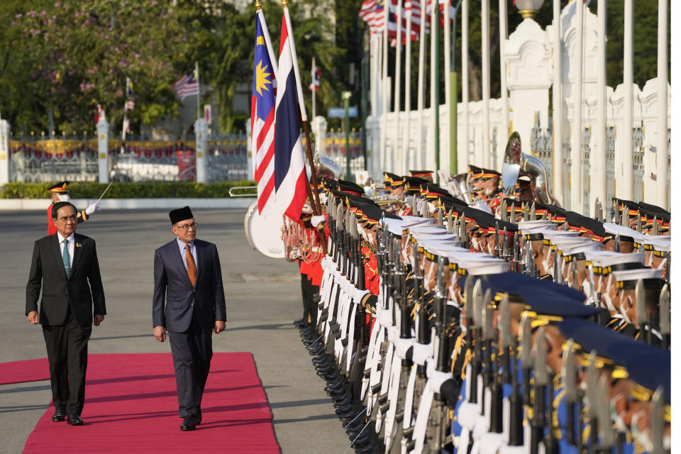 Malaysia's Prime Minister Anwar Ibrahim, right, escorted by Thailand's Prime Minister Prayuth Chan-ocha reviews an honor guard during a welcoming ceremony at the Government House in Bangkok, Thailand, Thursday, Feb. 9, 2023. (AP Photo/Sakchai Lalit)