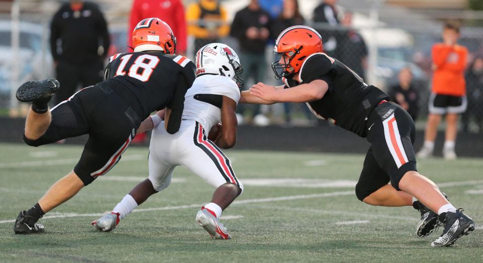 Hoover defensive ends Mike Shimek (18) and Drew Logan (right) converge on McKinley quarterback Amarion Williams during a Sept. 24, 2021 high school football game at Memorial Stadium.