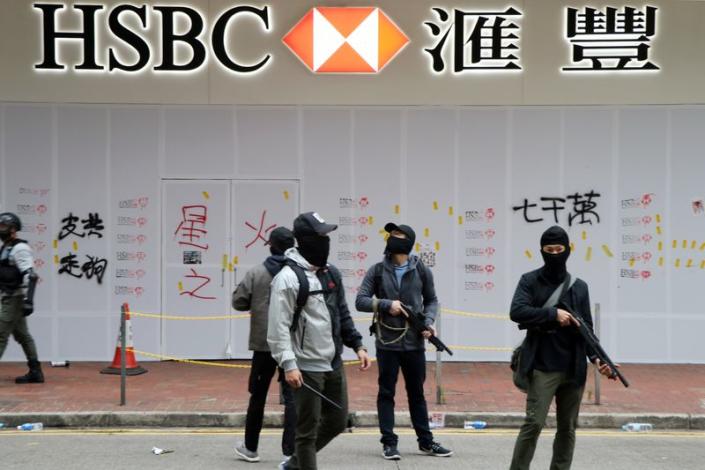 Armed undercover police officers guard a vandalized HSBC bank branch in Wan Chai during demonstrations on the New Year's Day in Hong Kong
