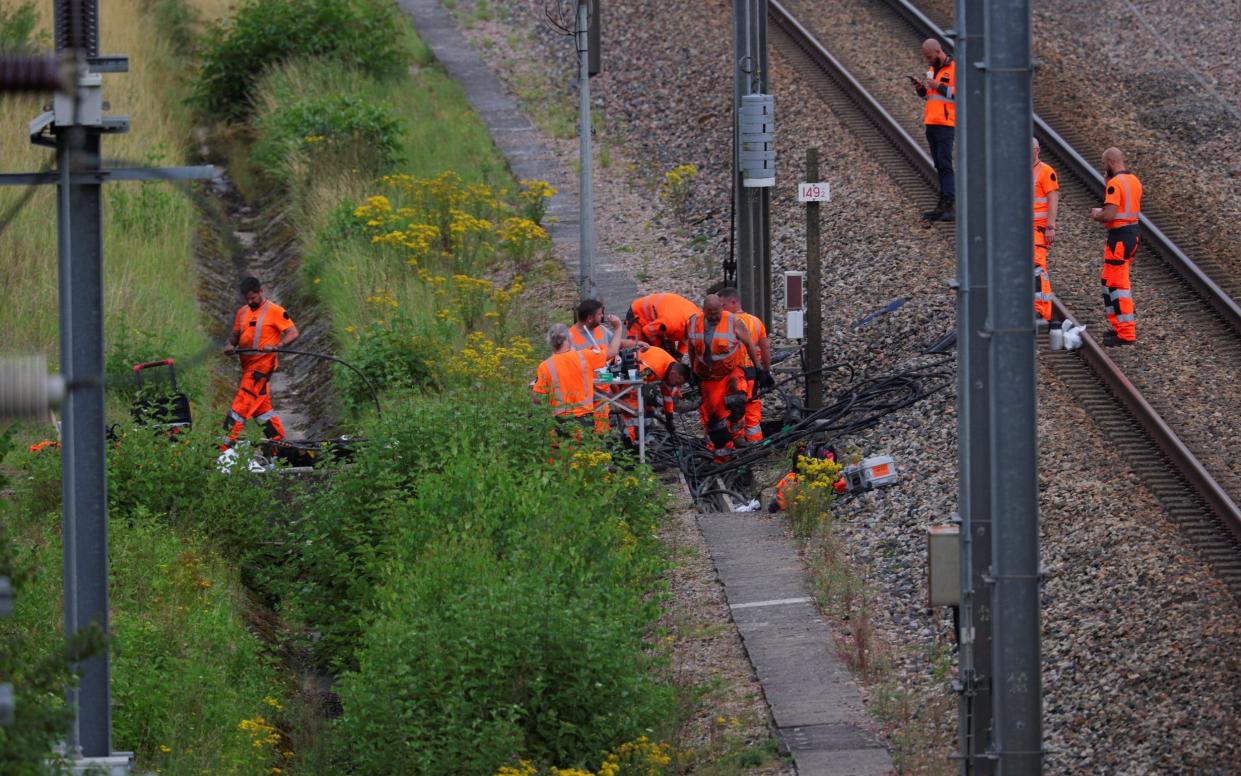 SNCF railway workers and police officers work at the site where saboteurs targeted France's high-speed train network