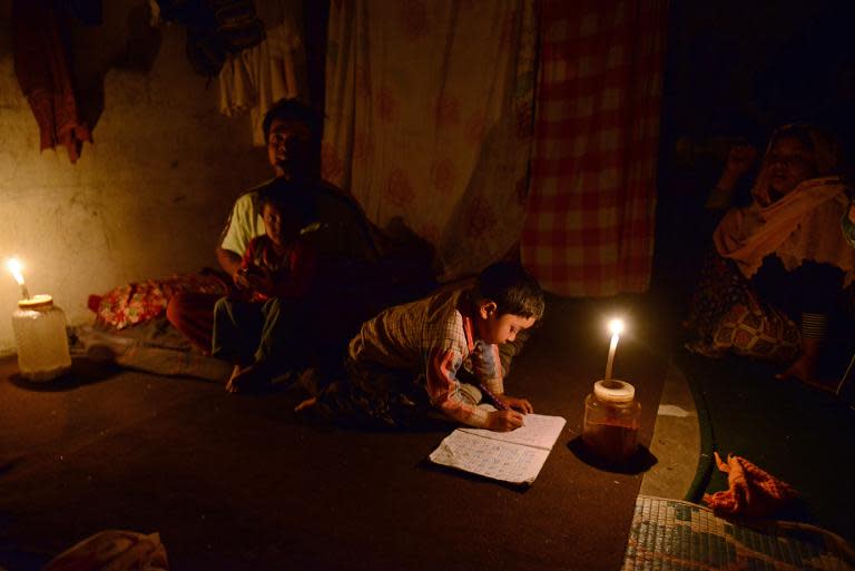 Refugee Amir Hussain (L), a Rohingya Muslim from Myanmar, watches his young son doing schoolwork by candlelight in their rented apartment in Kathmandu, on March 13, 2014