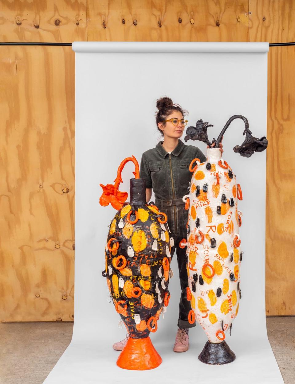 a woman standing next to large vases