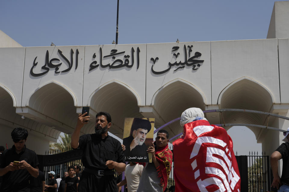 Supporters of Iraqi Shiite cleric Muqtada al-Sadr, seen in poster, protest in front the Supreme Judicial Council, in Baghdad, Iraq, Tuesday, Aug. 23, 2022. Dozens of supporters of al-Sadr, an influential Shiite cleric in Iraq, rallied on Tuesday in Baghdad’s heavily-fortified Green Zone, demanding the dissolution of parliament and early elections. The demonstration underscored how intractable Iraq's latest political crisis has become. (AP Photo/Hadi Mizban)