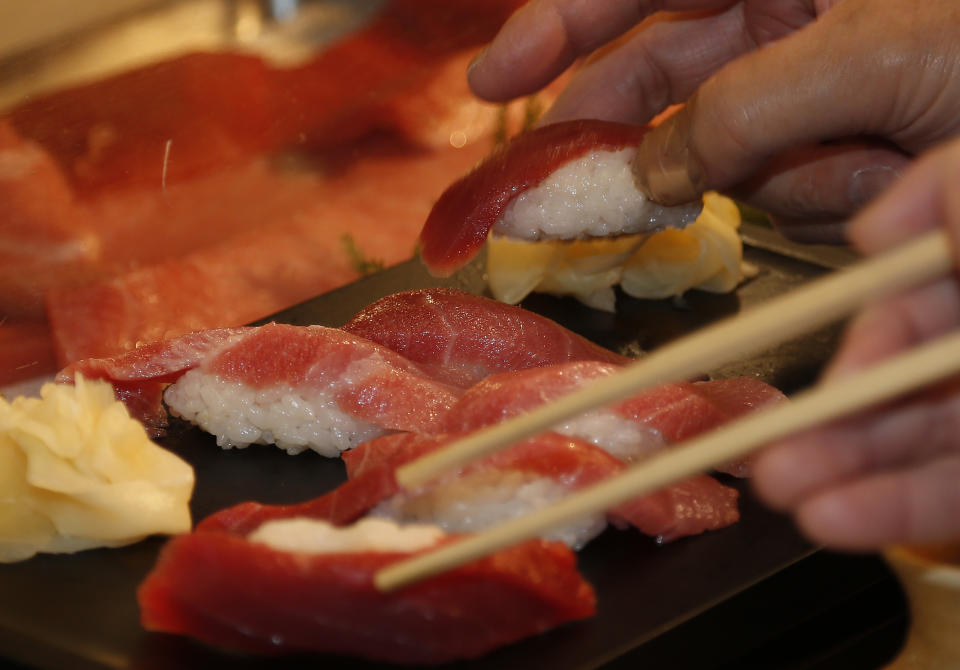 Customers take sushi of a bluefin tuna which was bought by sushi restauranteur Kiyoshi Kimura at the year's celebratory first auction, at his restaurant near Tsukiji fish market in Tokyo, Sunday, Jan. 5, 2014. Kimura paid 7.36 million yen (about $70,000) for the 507-pound (230-kilogram) bluefin tuna in the auction, just one-twentieth of what he paid a year earlier despite signs the species is in serious decline. (AP Photo/Shizuo Kambayashi)