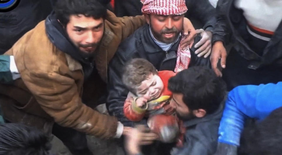 In this citizen journalism image made from Wednesday, Jan. 22, 2014 video provided by Nur Media Center, an anti-government activist group, which has been authenticated based on its contents and other AP reporting, one of the men holds 14-month-old Ghina Khalil after they dig her out of rubble in Aleppo, Syria. The toddler was pulled out after men pulled aside rocks, concrete rubble and dust to free her, caught under a smashed building, bombed by the government forces in the area of Masaraniyeh in Aleppo. (AP Photo/Nur Media Center)