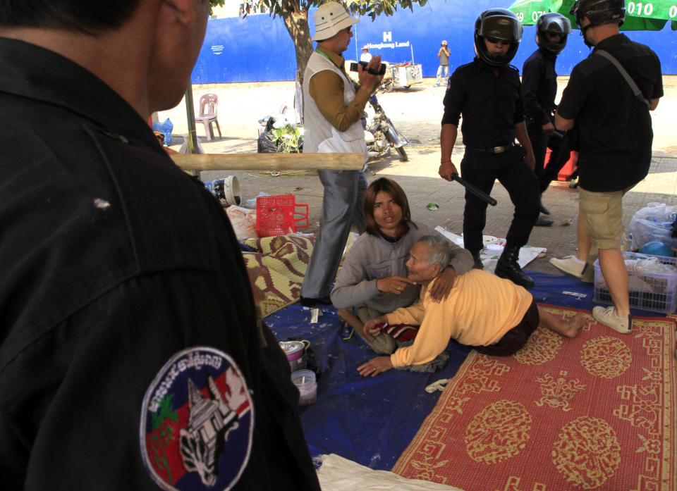 Security officers try to move the opposition supporters, center, of Cambodian National Rescue Party on a rally in Phnom Penh, Cambodia, Saturday, Jan. 4, 2014. Cambodian police have pushed out about 1,000 anti-government demonstrators from a park in the capital Phnom Penh, a day after four people were killed in a crackdown on a labor protest. (AP Photo/Heng Sinith)