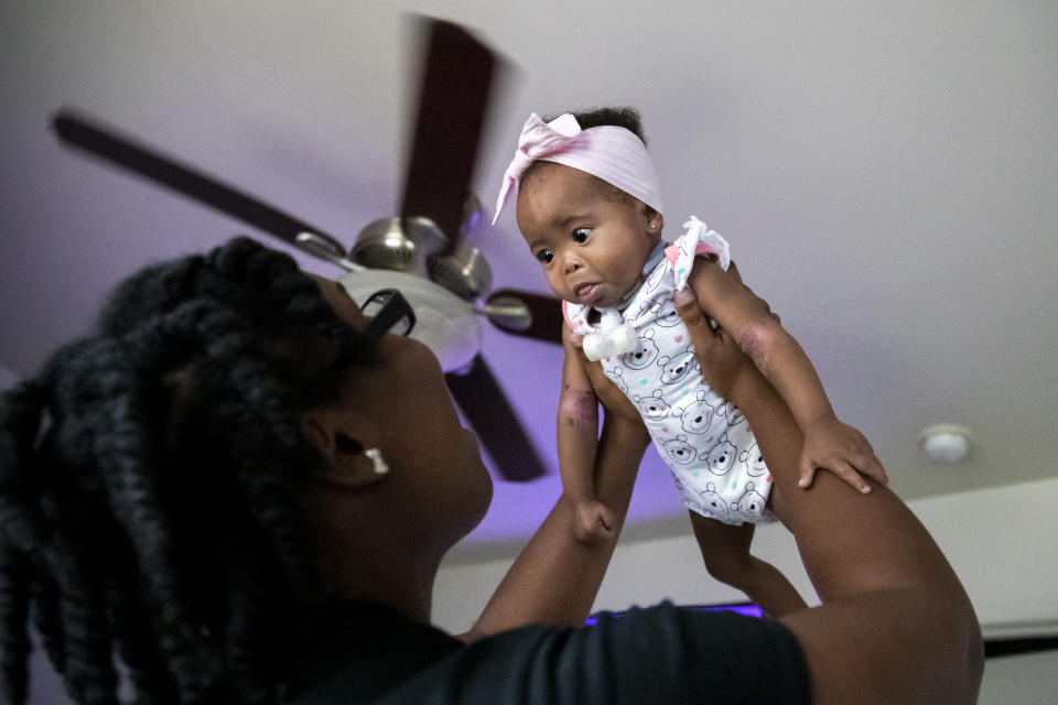 Tyesha Young, who lost her hospital job during the pandemic, tries to cheer up her baby Jalayah Johnson after a nap at their home in Waggaman, La., Friday, July 2, 2021. More than $7,000 behind on rent, Young had hoped a program in Louisiana would bail her out and allow her family to avert eviction in the coming weeks. But the 29-year-old mother of two from Jefferson Parish is still waiting to hear whether any of the $308 million available from the state for rental assistance and utility payments will give her a lifeline. She applied for money last year but never heard anything. ​(AP Photo/Sophia Germer)