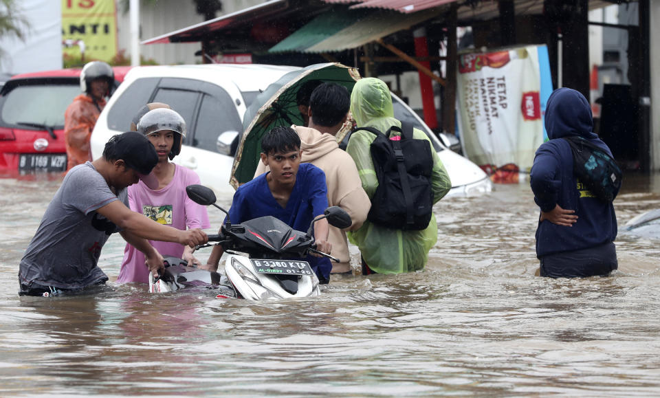 Indonesian people wade through floodwaters at Jatibening on the outskirt of Jakarta, Indonesia, Wednesday, Jan. 1, 2020. Severe flooding hit Indonesia's capital just after residents celebrating New Year's Eve, forcing a closure of an airport and thousands of inhabitants to flee their flooded homes. (AP Photo/Achmad Ibrahim)