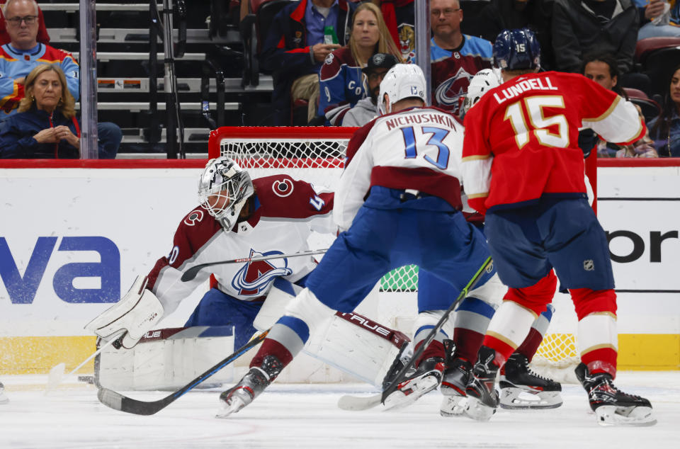 Colorado Avalanche goaltender Alexandar Georgiev (40) makes a save as Florida Panthers center Anton Lundell (15) pressures Avalanche right wing Valeri Nichushkin (13) during the first period of an NHL hockey game Saturday, Feb. 11, 2023, in Sunrise, Fla. (AP Photo/Reinhold Matay)