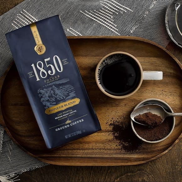 Package of premium "1850" ground coffee on wooden serving tray with coffee cup.