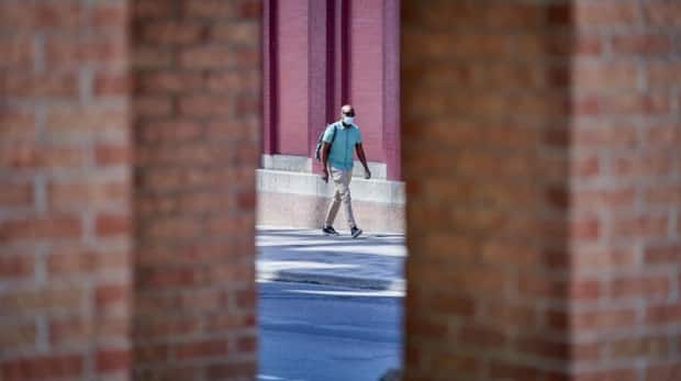 A masked pedestrian walks on O'Connor Street in downtown Ottawa during the COVID-19 pandemic. (David Richard/Radio-Canada - image credit)