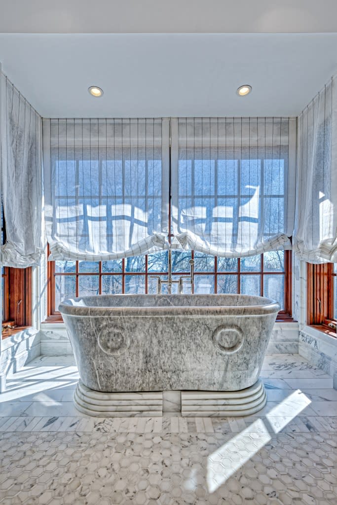 A bathroom with a prominent marble soaking tub. Bernard Coulson