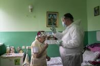 In this photo taken on Thursday, May 28, 2020, Father Yaroslav Rokhman, Ukrainian Greek Catholic Church priest, wearing protective gear to protect against coronavirus, blesses a patient of a hospice in Ivano-Frankivsk, Ukraine. Rokhman, a priest in the Ukrainian Greek Catholic Church, is pleased to be able to return to performing one of a cleric's most heartfelt duties. As the coronavirus pandemic's grip on Ukraine slowly recedes, priests received permission on May 22 to again hold services and visit the sick. (AP Photo/Evgeniy Maloletka)