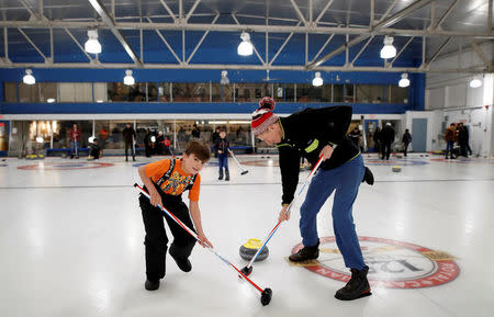 A Yazidi refugee from Kurdistan learns curling with club member Jim Creeggan (R), at the Royal Canadian Curling Club during an event put on by the "Together Project", in Toronto, March 15, 2017. REUTERS/Mark Blinch