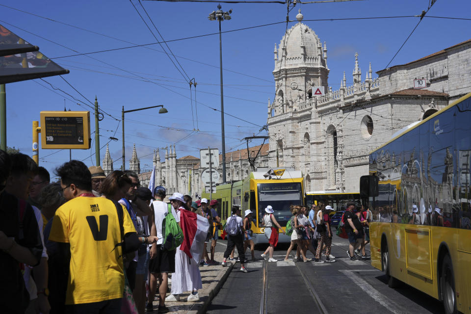 World Youth Day pilgrims queue to catch public transport outside the 16th century Jeronimos monastery, in the background, in Lisbon, Tuesday, Aug. 1, 2023. Pope Francis will visit the monastery when he arrives Aug. 2 to attend the international event that is expected to bring hundreds of thousands of young Catholic faithful to Lisbon and goes on until Aug. 6. (AP Photo/Ana Brigida)