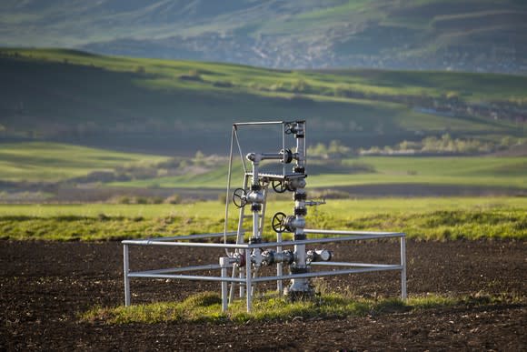 A natural gas wellhead in the middle of a field.