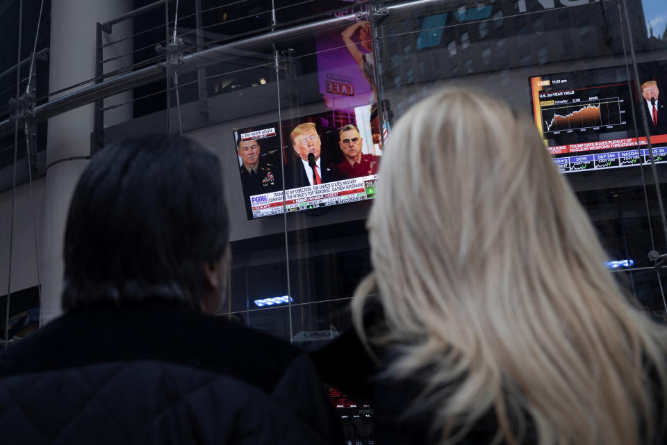 People watch as U.S. President Donald Trump is seen on screens delivering a statement from the White Housein New York