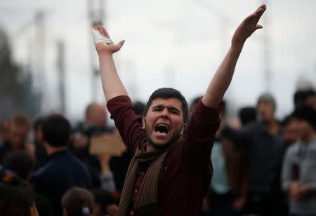 A migrant shouts slogans as he is blocking the railway track at the Greek-Macedonian border, near the village of Idomenii, Greece March 12, 2016. REUTERS/Stoyan Nenov