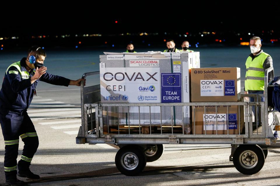 Airport employees push a cart carrying first shipment of Covid-19 jabs at the Pristina International Airport on March 28, 2021. - Kosovo received on March 28, 2021 its first shipment of Covid-19 jabs which were delivered through the UN-backed Covax scheme to help poorer nations that had delays in reaching Balkan nations. The batch of 24,000 doses of the AstraZeneca/Oxford vaccine was delivered as Kosovo, like the rest of its Balkans neighbours, is fighting a significant surge in the number of coronavirus infections. (Photo by - / AFP) (Photo by -/AFP via Getty Images)