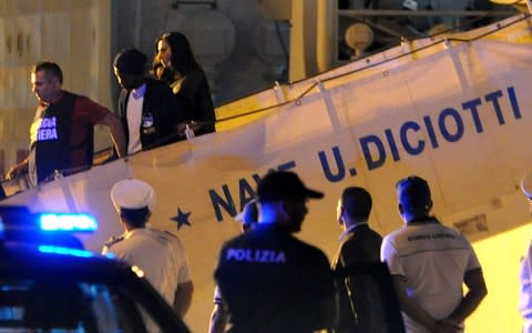 A migrant disembarks, escorted by police, from Italy's Diciotti coast guard vessel in the port of Trapani on July 12, 2018 - Credit: AFP