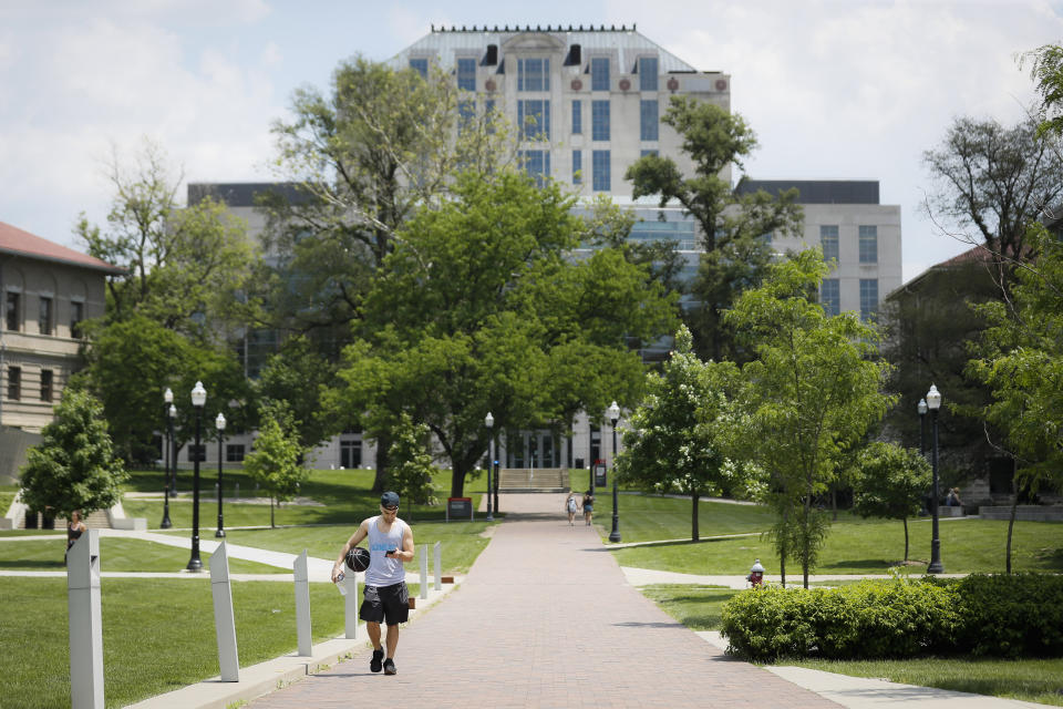 FILE - In this May 18, 2019 file photo pedestrians walk towards The Ohio State University's athletics facilities in Columbus, Ohio. Mike Drake, the president of The Ohio State University says he'll retire from that role next year. Drake's five-year tenure at one of the nation's largest universities has included strategic successes, such as record numbers for the school in applications, graduates, research expenditures and donor support. But it also has been marred by scandals involving the university's marching band, a prominent football coach and a former team doctor accused of widespread sexual abuse.(AP Photo/John Minchillo, File)