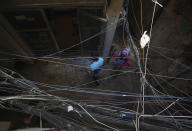 FILE - In this May 24, 2014, file, photo, Palestinian refugees walk under electricity cables in an alley in the Palestinian refugee camp of Shatila in Beirut, Lebanon. Lebanon's energy minister said Thursday, July 16, 2020 the country's worsening economic crisis is making it increasingly difficult to attract investors for its ailing electricity sector.(AP Photo/Bilal Hussein, File)