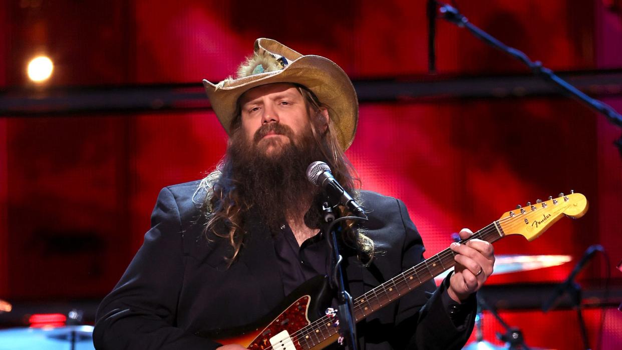 chris stapleton playing a guitar and looking out at the audience during a performance