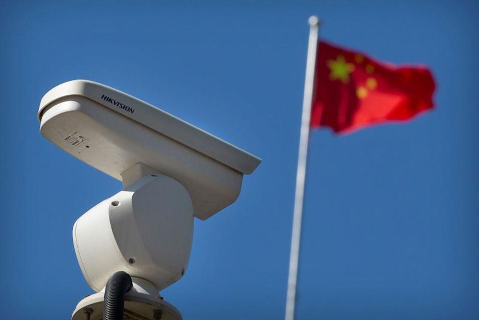 Una bandera china ondea cerca de una cámara de seguridad que monitorea una intersección de tráfico en Beijing, el martes 8 de octubre de 2019. (Crédito: Mark Schiefelbein/AP)