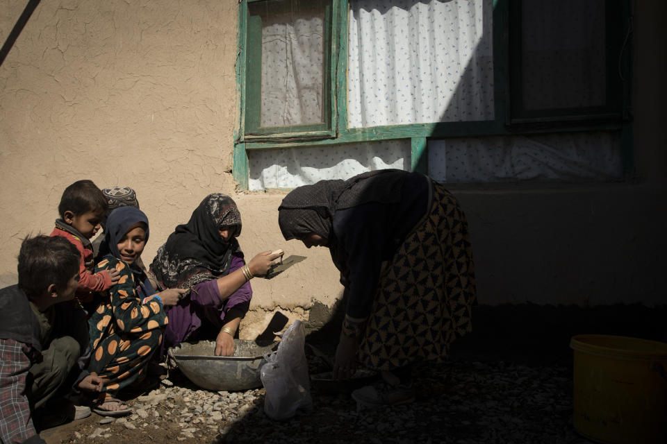 Mina Ahmed, center, is helped by her children as she prepares a cement mixture to repair the walls and floor of her war-ravaged home in Salar village, Wardak province, Afghanistan, Sunday, Oct. 24, 2021.In urban centers, public discontent toward the Taliban is focused on threats to personal freedoms, including the rights of women. In Salar, these barely resonate. The ideological gap between the Taliban leadership and the rural conservative community is not wide. Many villagers supported the insurgency and celebrated the Aug. 15 fall of Kabul which consolidated Taliban control across the country. (AP Photo/Oriane Zerah)