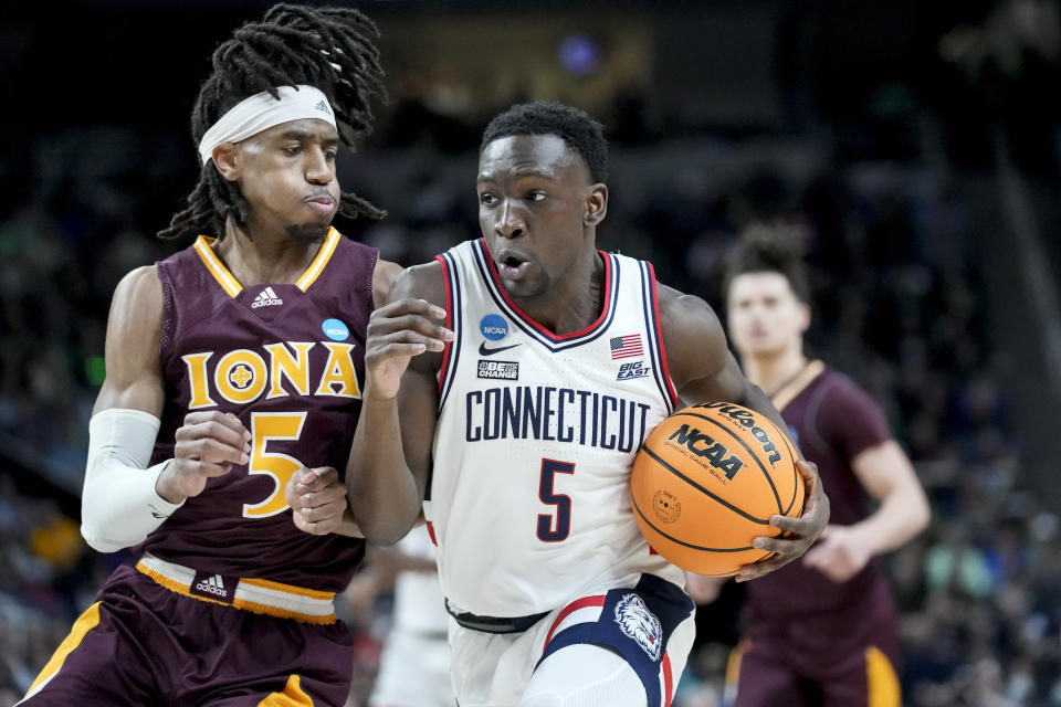 Connecticut's Hassan Diarra, center, drives against Iona's Daniss Jenkins, left, in the first half of a first-round college basketball game in the NCAA Tournament, Friday, March 17, 2023, in Albany, N.Y. (AP Photo/John Minchillo)