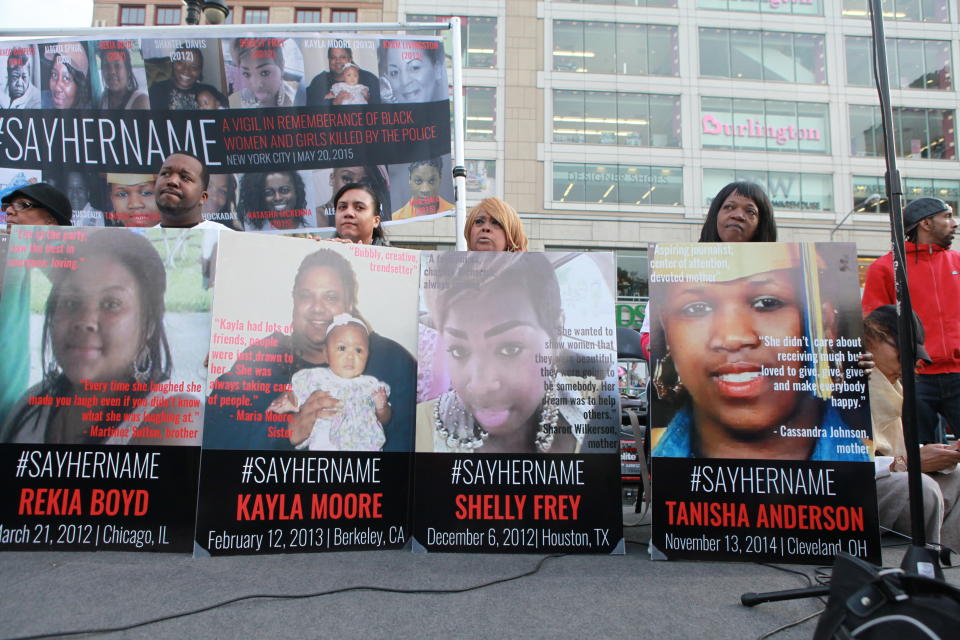 Family members on stage at the vigil, holding placards in remembrance of their sisters, daughters, nieces, and mothers.