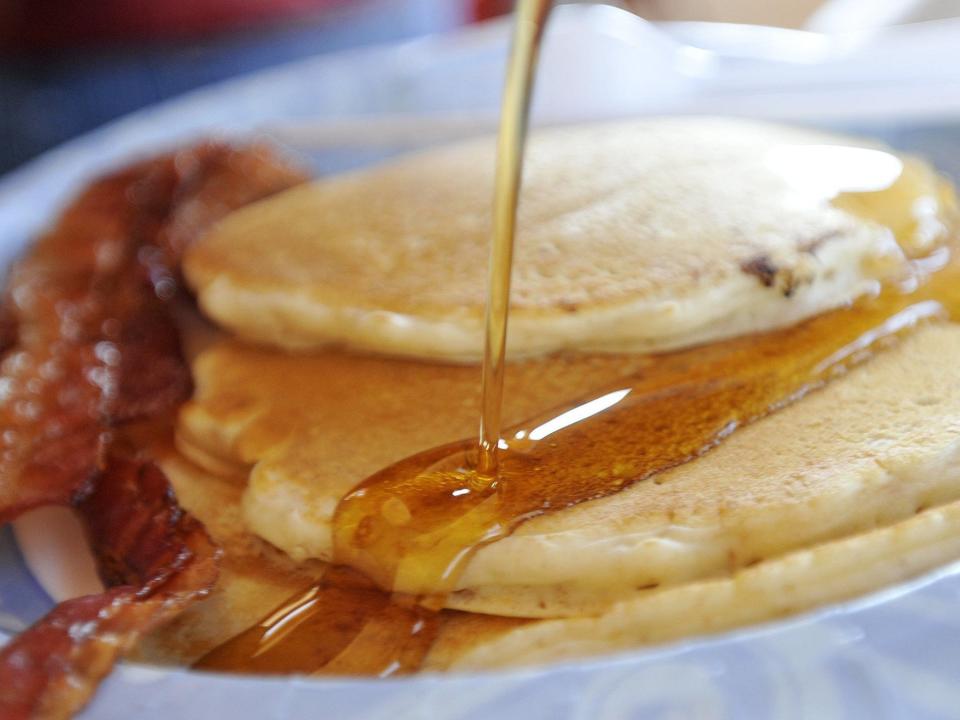 pancakes being drizzled with maple syrup