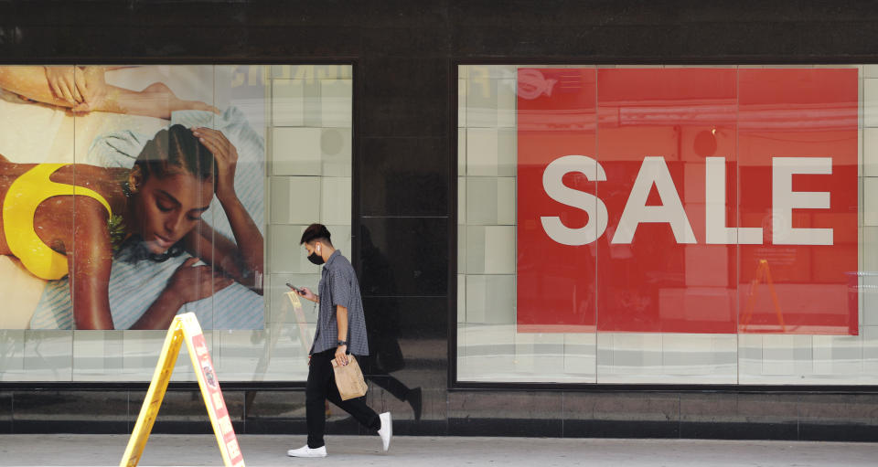 A man wearing a mask to protect against COVID-19 pass a sale sign and advertising at a business in San Antonio, Monday, July 20, 2020. Cases of COVID-19 continue to spike in Texas. (AP Photo/Eric Gay)