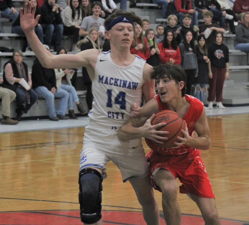 Onaway junior guard Austin Veal (right) looks to get past defending Mackinaw City senior guard Lars Huffman (14) during the second half on Thursday.