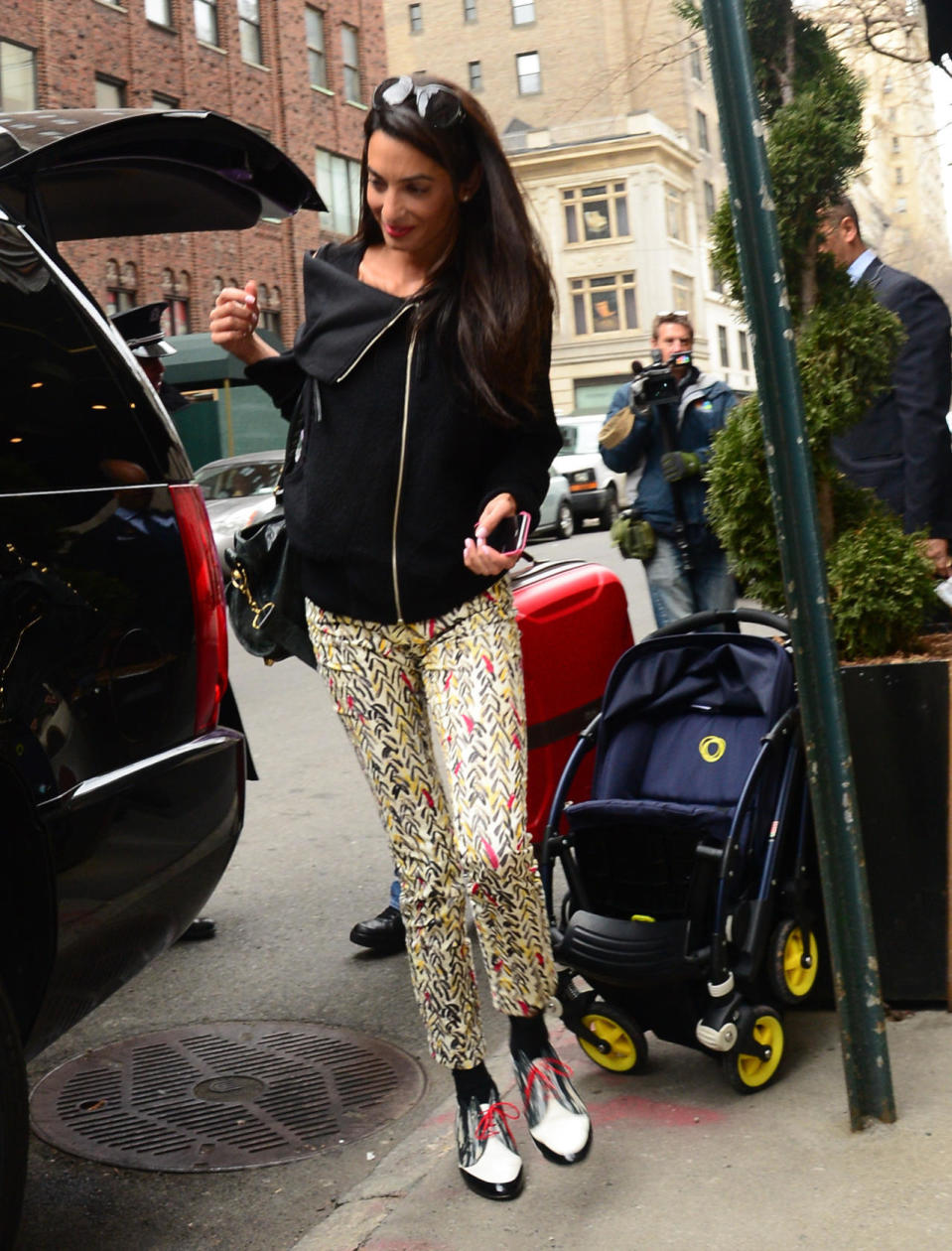 Amal Alamuddin in patterned pants, brogues, and black jacket.